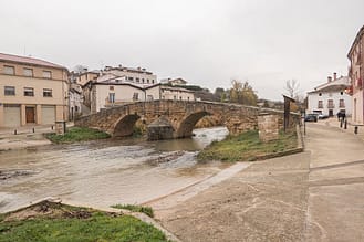 El río Iranzu, crecido, discurre por debajo del puente medieval o románico de Villatuerta, del siglo XIII.